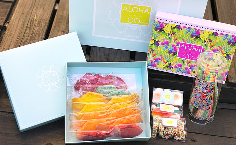 写真手前から■５つのフレーバー（リリコイ、バニラ、マンゴー、レッドベルベット、ブルーベリー）の魚形クッキーは毎日店内で焼き上げている。14枚入り＄14.95<br />
■色とりどりのグミが入ったキャンディボックス1個＄3.75〜<br />
