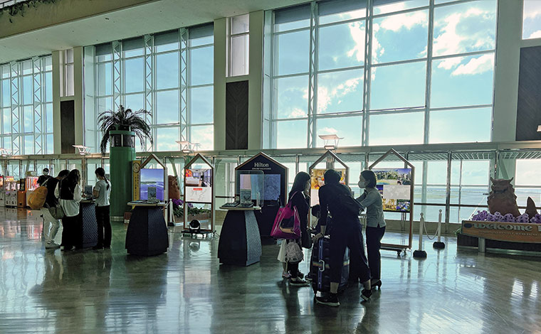 那覇空港2階ロビーにあるヒルトングランドバケーションズのデスク。ジンベエザメの壁面ポスターはすぐ向かい側にあります！