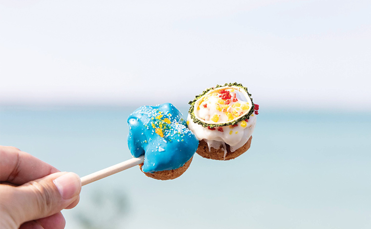 8月にオープンしたばかりの「De:（でころん）」のちょっと変わったサーターアンダギー。（白い方がゴーヤチャンプルー、青い方がソルティマンゴー）　写真提供：Sesoko Masayuki