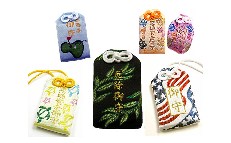 左上から時計回り）ゴルフお守り8ドル、交通安全お守り8ドル、身守り8ドル、星条旗お守り8ドル、厄除お守り8ドル、交通安全お守り8ドル<br />
写真提供：ハワイ金刀比羅神社・ハワイ太宰府天満宮